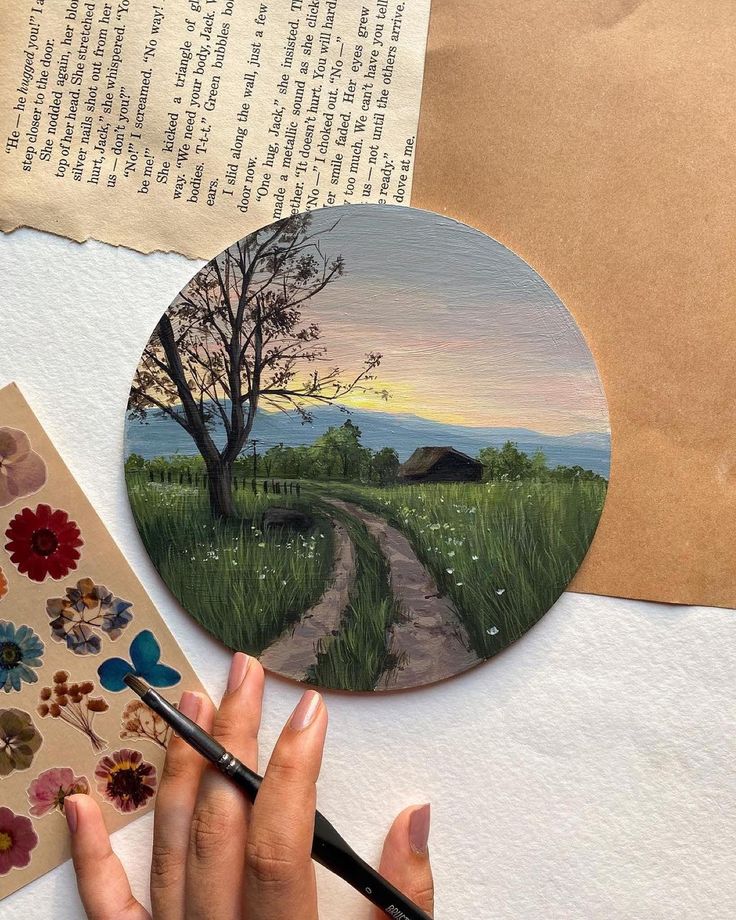 someone is painting a landscape on a piece of paper