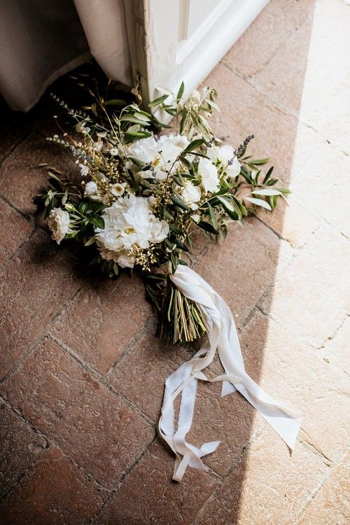 a bridal bouquet laying on the ground next to a door with ribbon around it