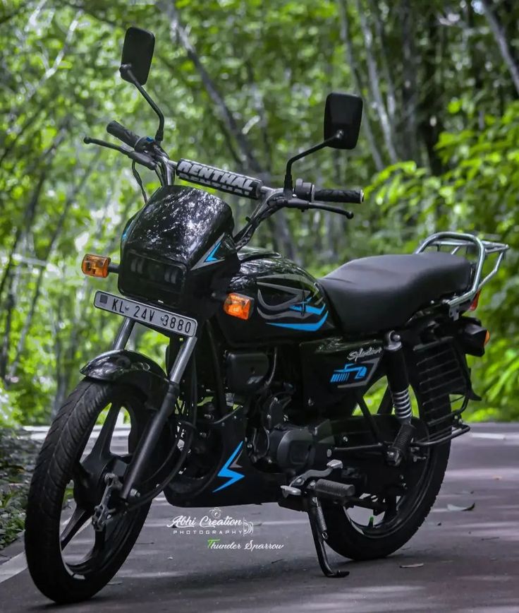 a black motorcycle parked on the side of a road in front of some green trees