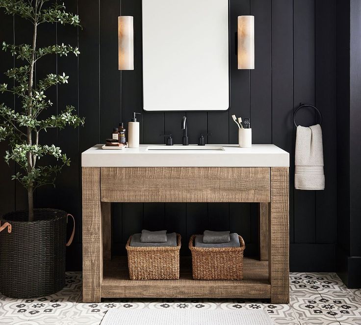 a bathroom with black walls and white tile flooring, two wicker baskets under the sink