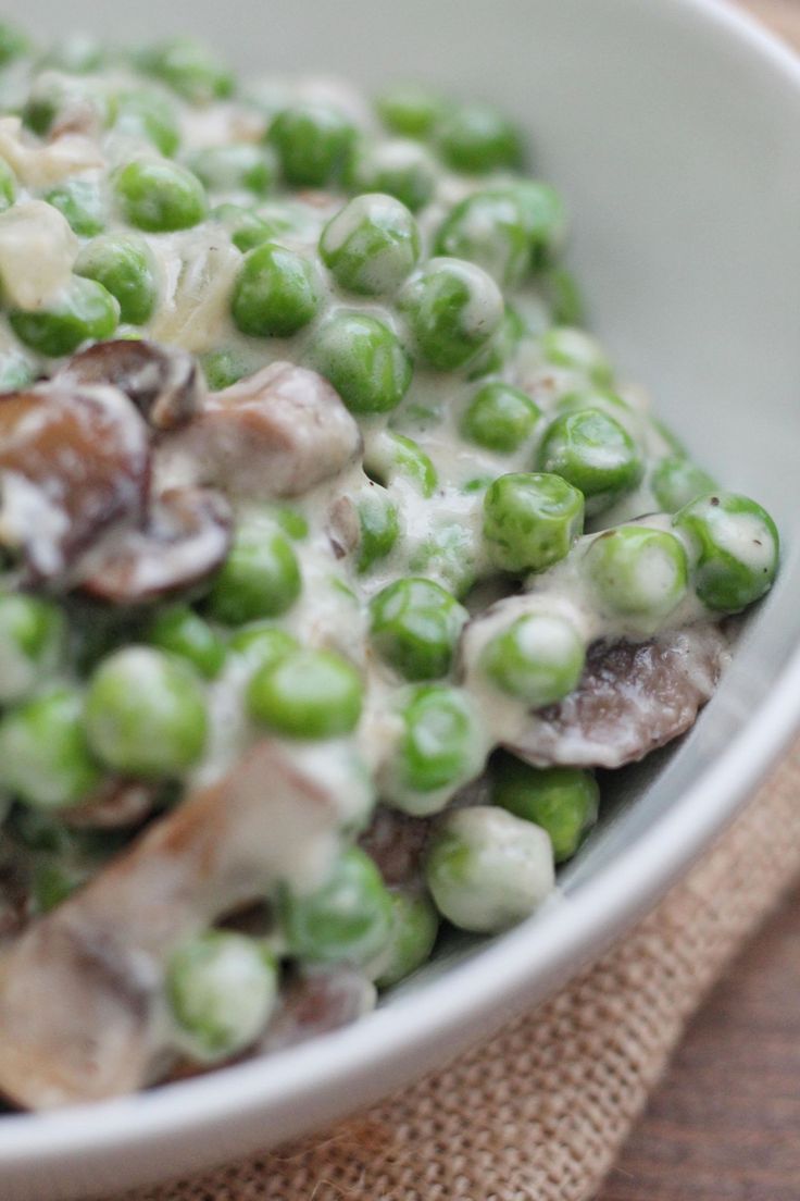 a white bowl filled with peas and mushrooms