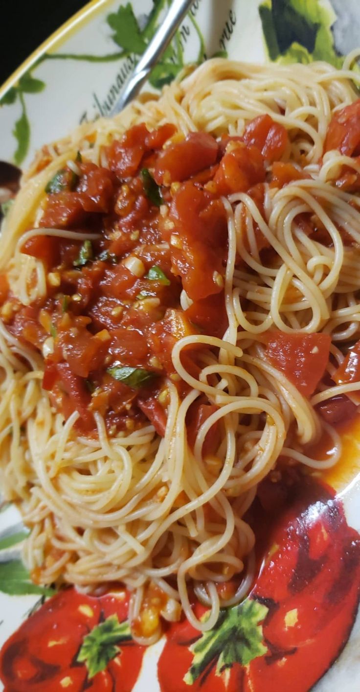 spaghetti with tomato sauce and corn on the side sitting on a flowered plate, ready to be eaten