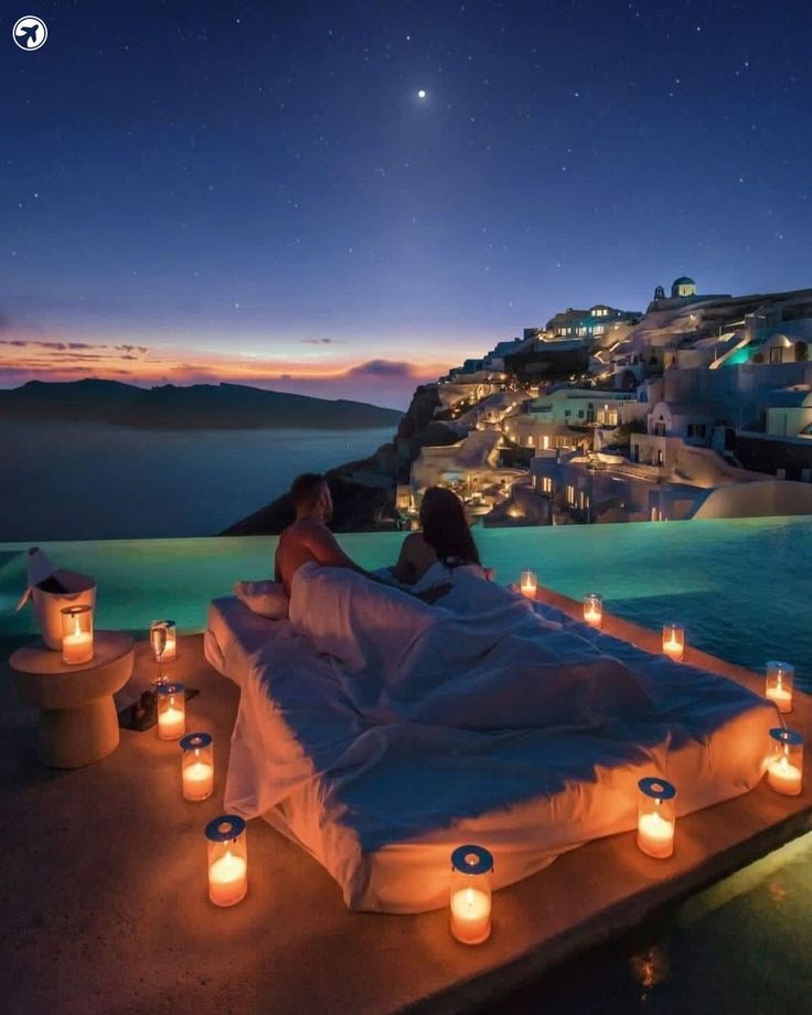 two women sitting on a bed with candles in front of them and the sky is full of stars