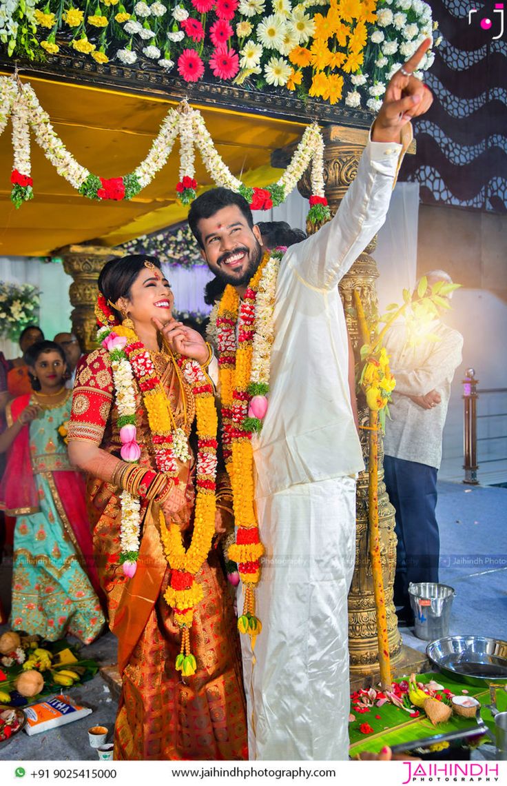 a man and woman standing next to each other in front of a stage with flowers on it