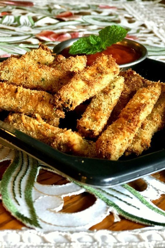 some fried food on a black plate with dipping sauce in the bowl next to it