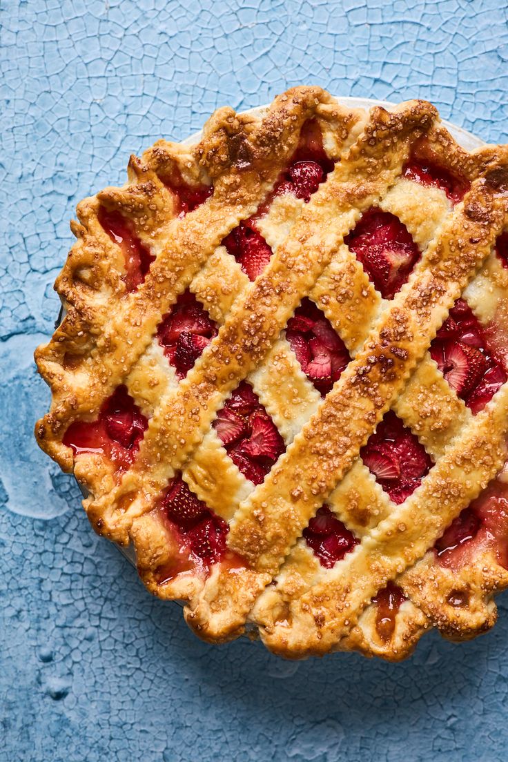 an overhead view of a strawberry pie on a blue surface