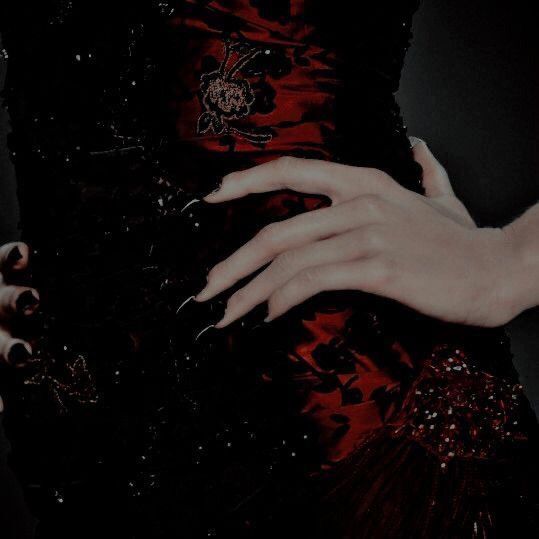 a woman's hand with black and red nail polish on her nails holding onto the dress