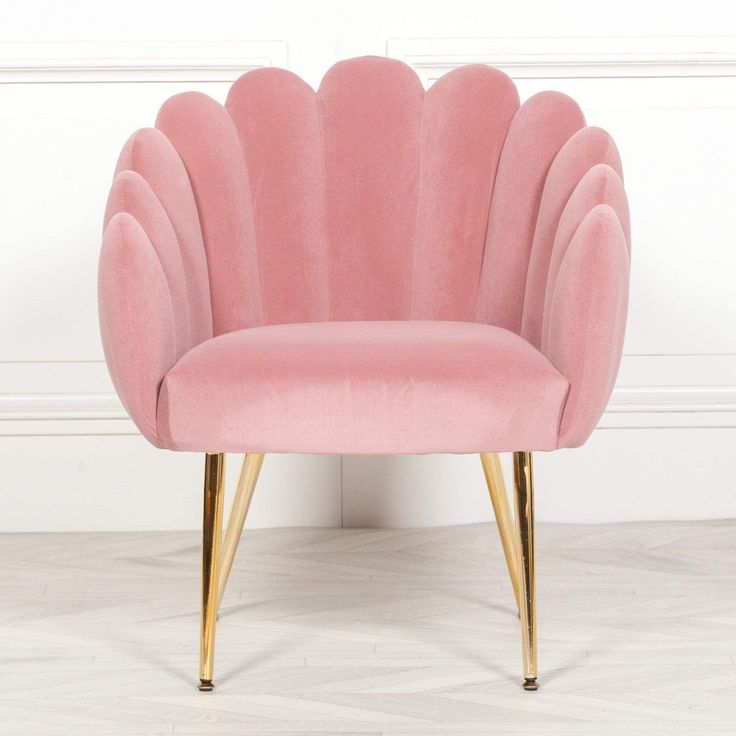 a pink chair with gold legs and a shell shaped backrest on a white floor