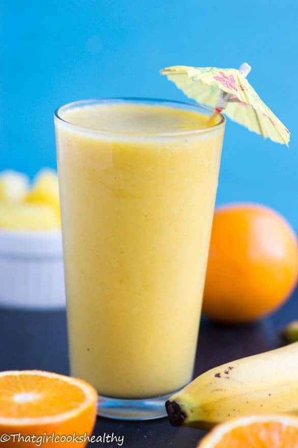 an orange and banana smoothie is garnished with an umbrella