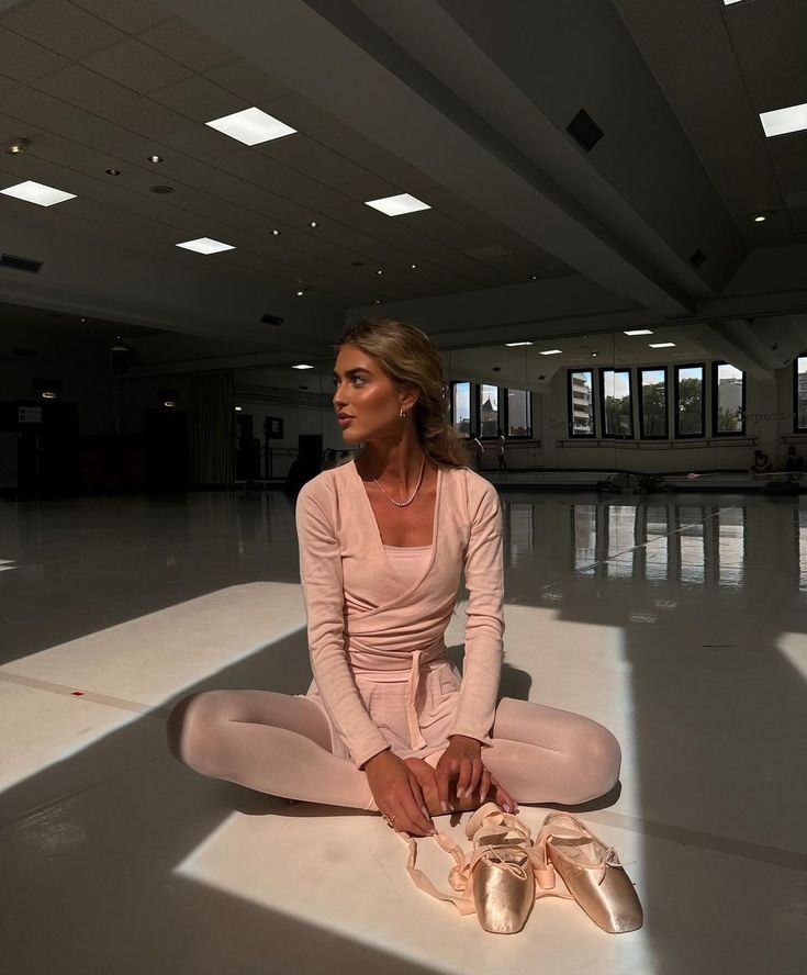 a woman sitting on the floor with ballet shoes