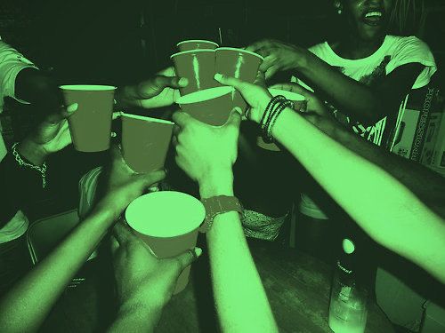 a group of people holding cups in the middle of a table with their hands together