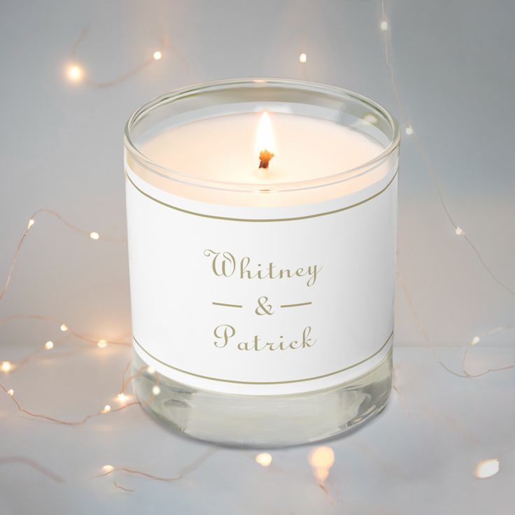 a white candle with the words whitney and patrick on it sitting in front of some lights