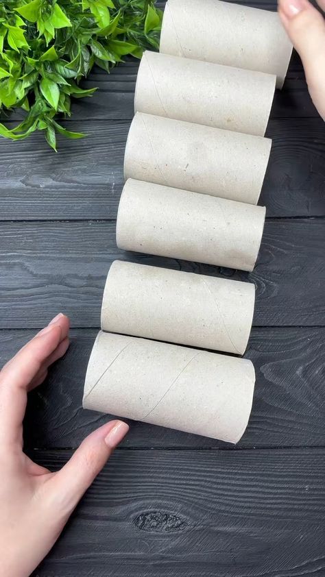 four rolls of toilet paper sitting on top of a wooden table next to a person's hand