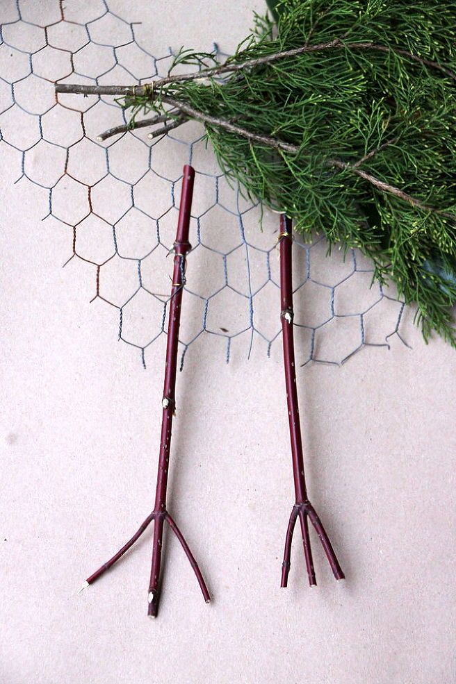 two pairs of scissors sitting on top of a table next to a branch and chicken wire