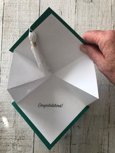 a hand holding an origami piece with congratulations written on it and a tassel hanging from the end