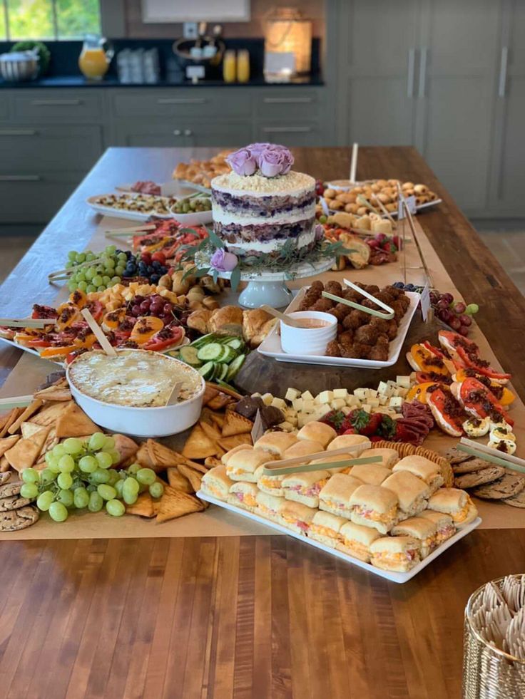 a wooden table topped with lots of trays of food next to a counter top