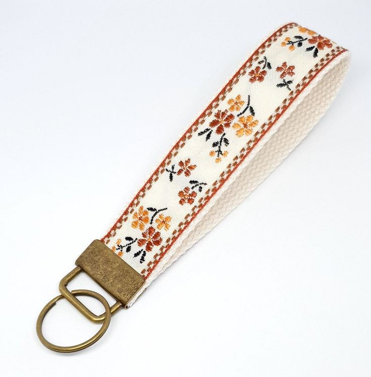 a white strap with orange flowers and gold buckles on an off - white background