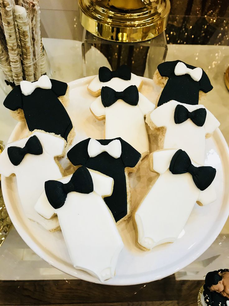 decorated cookies with black and white bow ties on a platter next to gold decorations