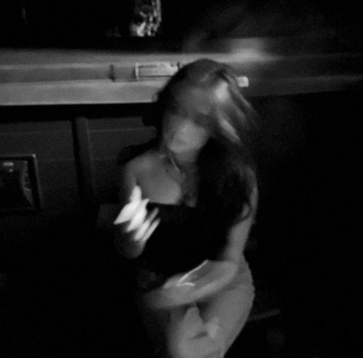 black and white photograph of a woman in the dark with her arms around her body