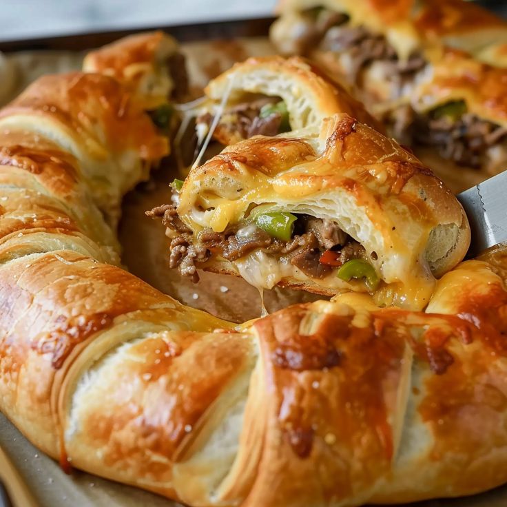 a close up of a pastry with meat and cheese in it on a tray next to a knife