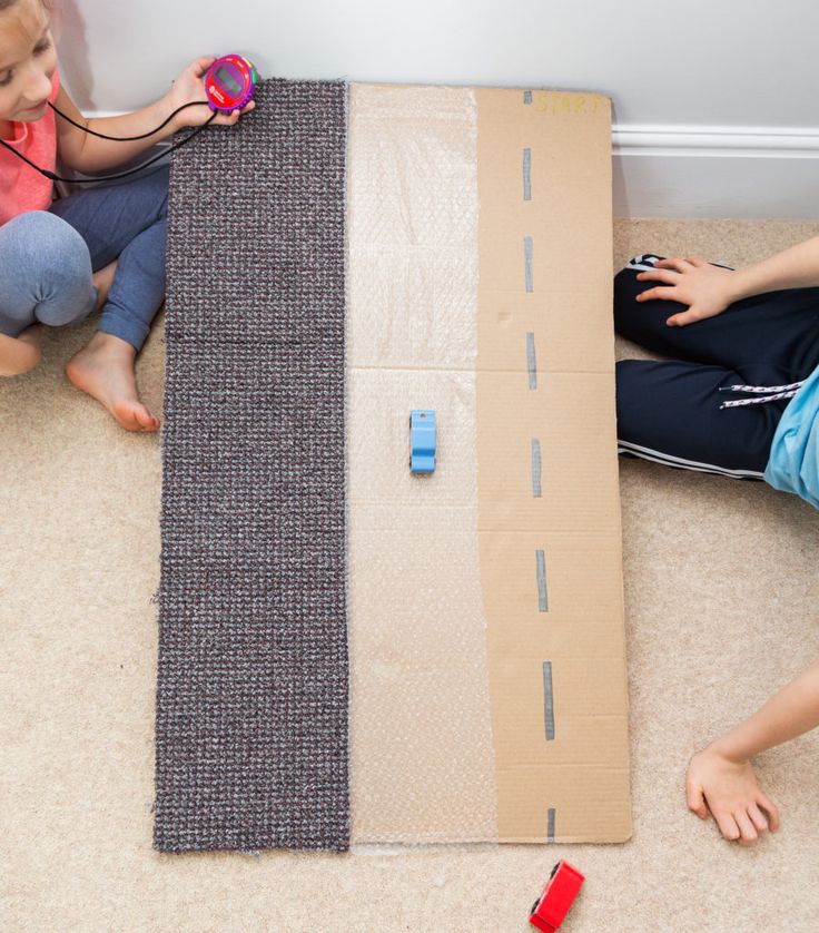 two children sitting on the floor next to cardboard boxes with electrical cords in each side