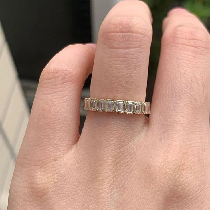 a woman's hand with a ring on it that has five stones in it