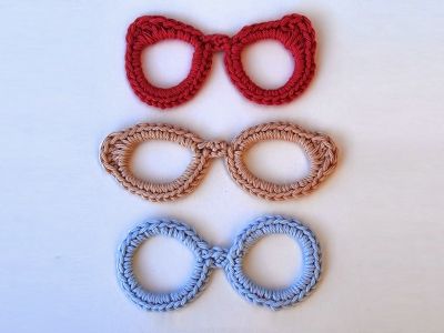 three pairs of eyeglasses and two rings on a white surface with red, blue, and brown beads