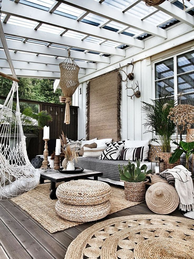 an outdoor living room with wicker furniture and plants on the floor, along with hanging baskets