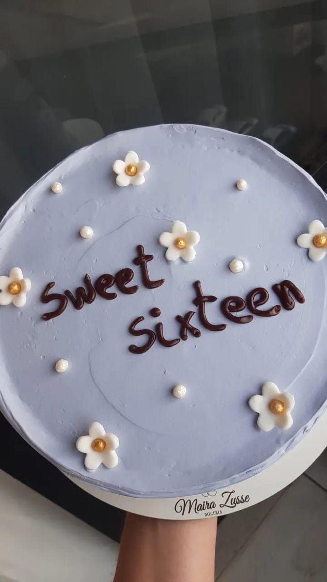 a cake with the words sweet sixteen written in frosting on it and daisies