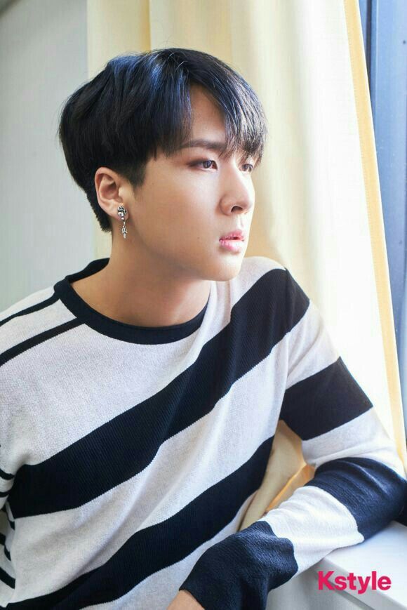 a young man sitting on top of a window sill wearing a striped shirt and black gloves