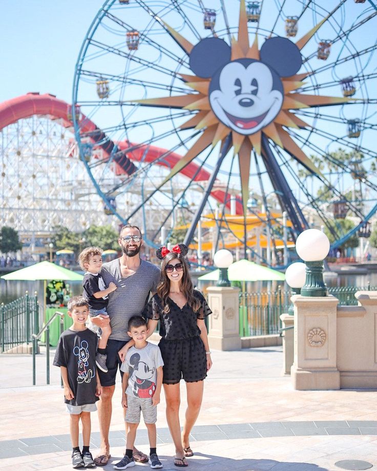 a family poses for a photo in front of the mickey mouse wheel at disney world