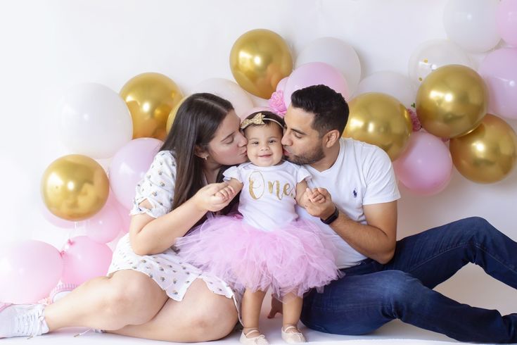 a man, woman and child are sitting in front of balloons