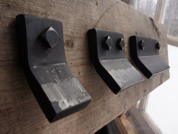 three metal knobs are mounted to the side of a wooden paneled window sill