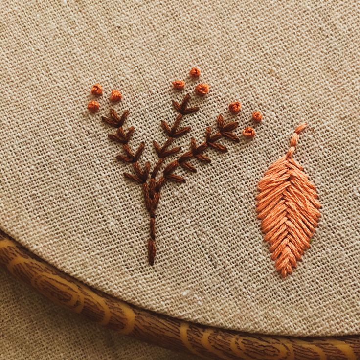 two embroidered leaves on the back of a piece of cloth, one orange and one brown