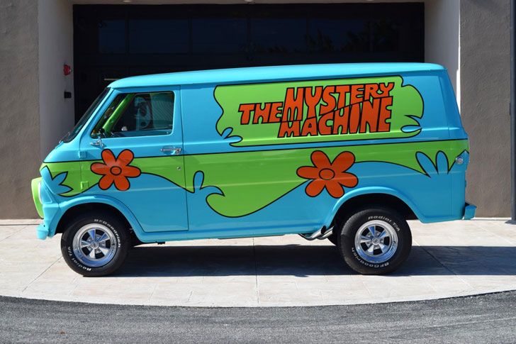 the van is parked in front of the garage with flowers painted on it's side