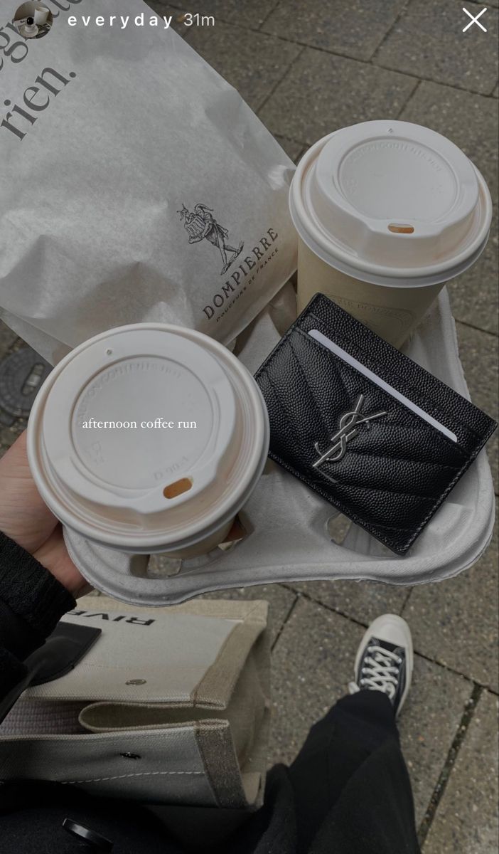 a person holding two coffee cups and a wallet