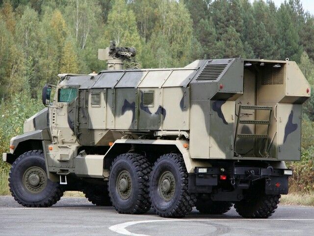 an army truck is parked on the side of the road with trees in the background