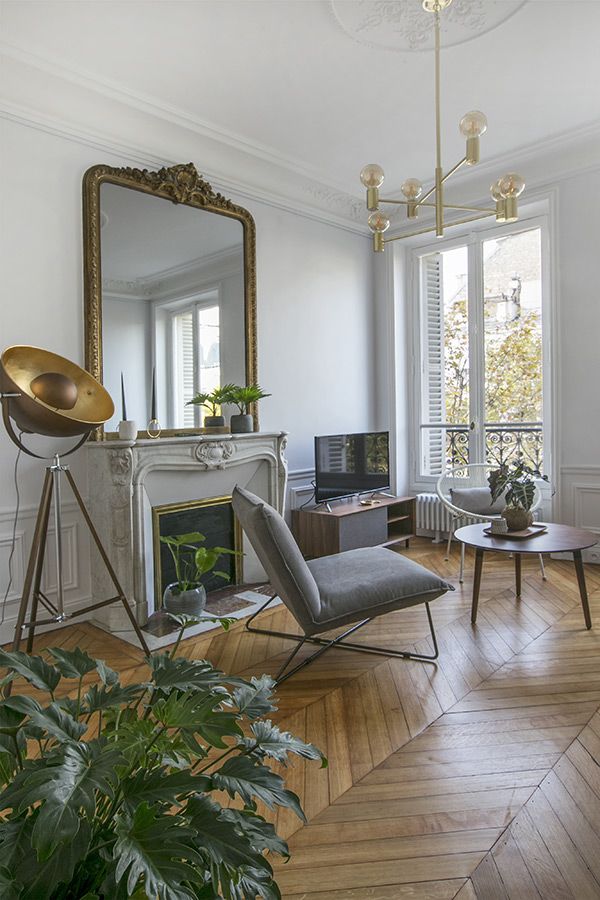 a living room filled with furniture and a fire place in front of a mirror on the wall