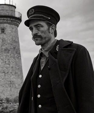 two men standing next to each other near a light house