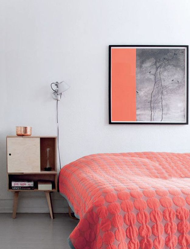 an orange bedspread in a white bedroom