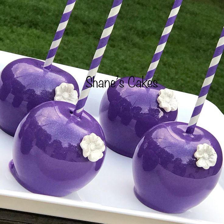 four purple apples with white flowers on them