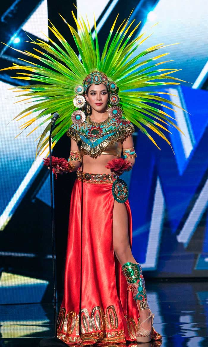 a woman in a red and gold costume is standing on stage with a large green plant