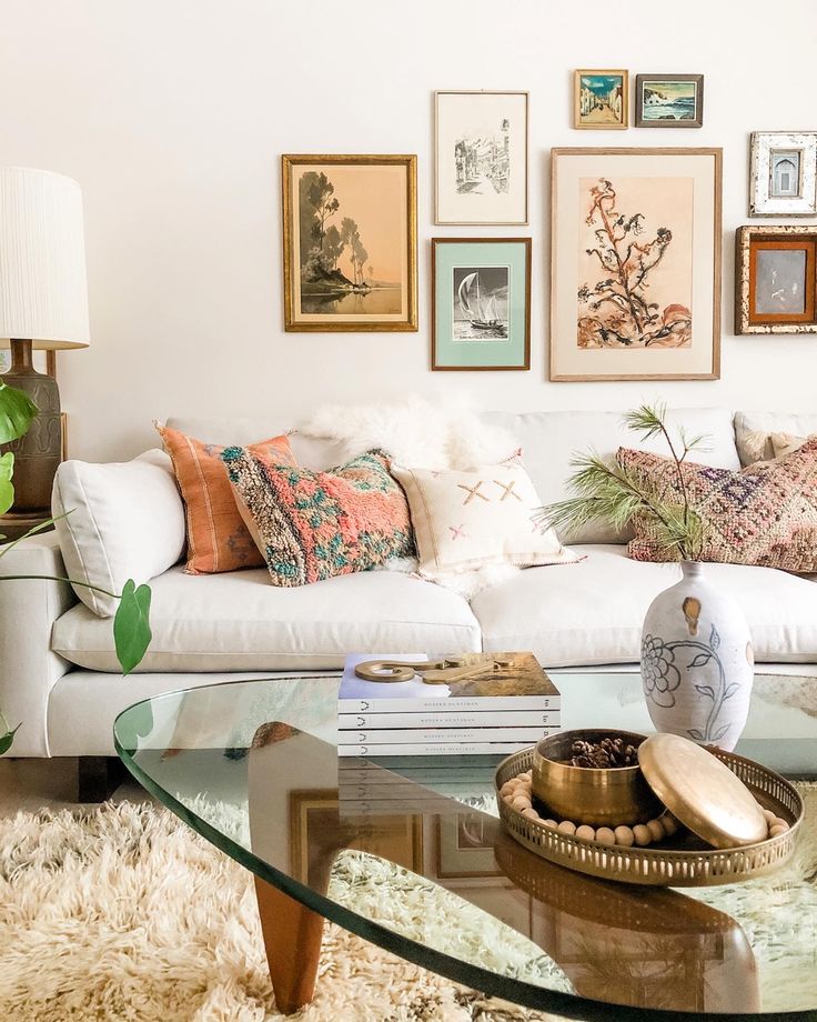 a living room filled with lots of furniture and pictures on the wall above it's glass coffee table