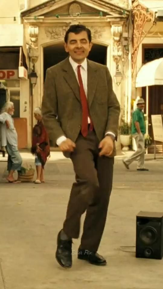 a man wearing a suit and tie standing in front of a speaker on the street