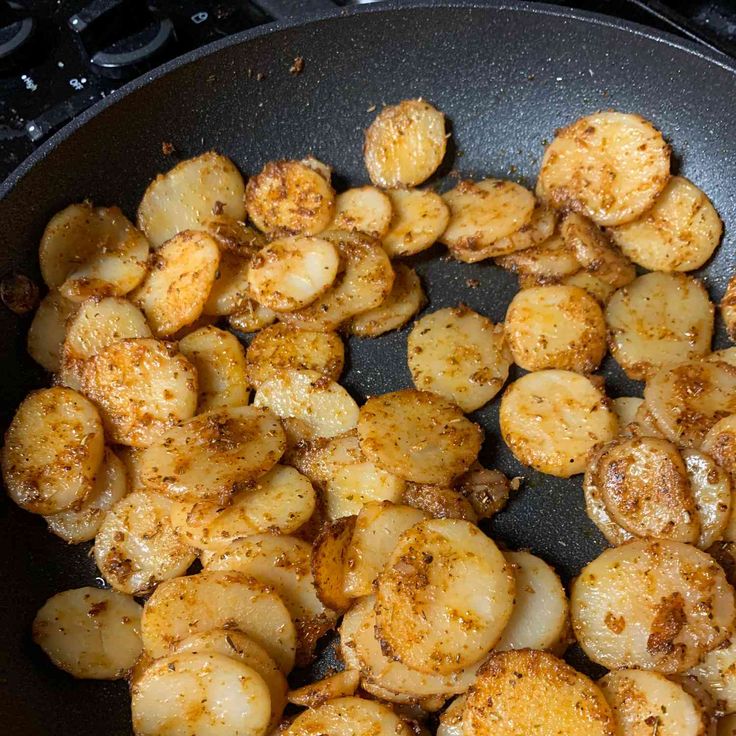 fried potatoes are being cooked in a frying pan