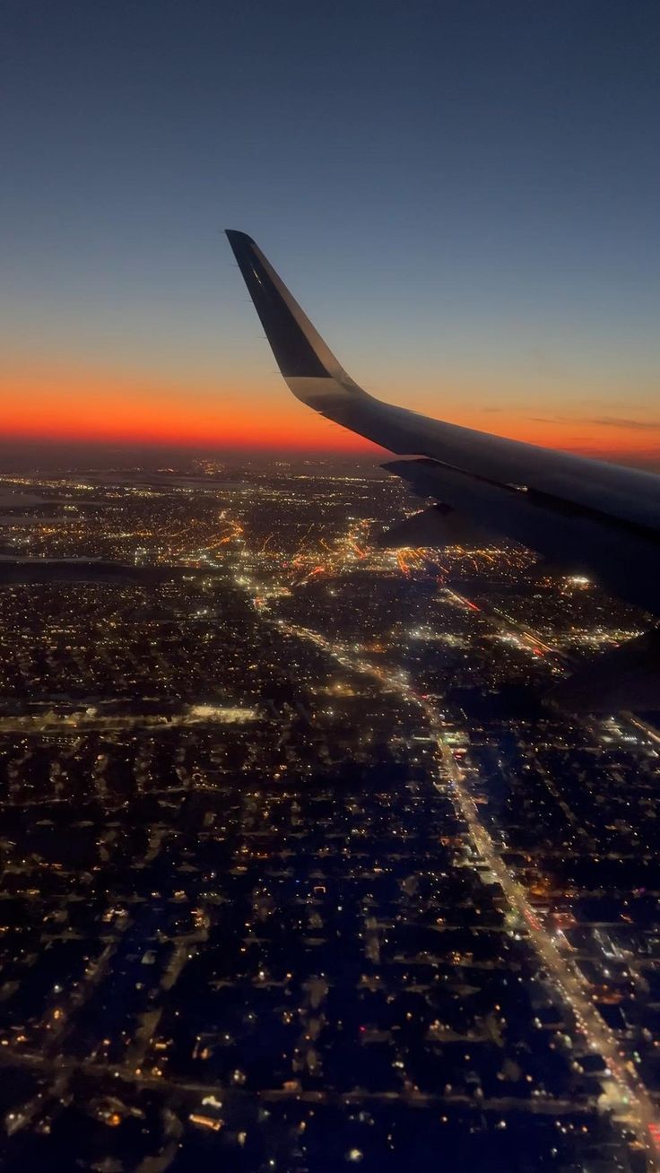 the wing of an airplane flying over a city at night