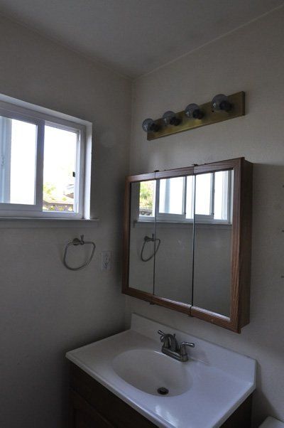 a bathroom with a sink, mirror and toilet paper dispenser on the wall