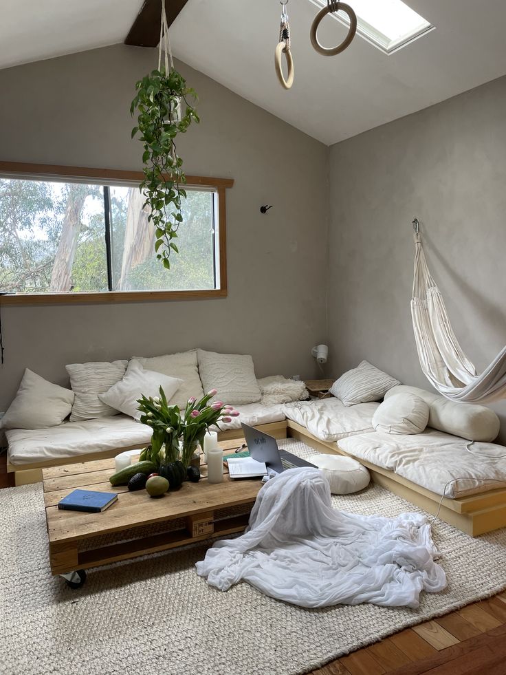 a living room filled with lots of furniture and a hammock hanging from the ceiling