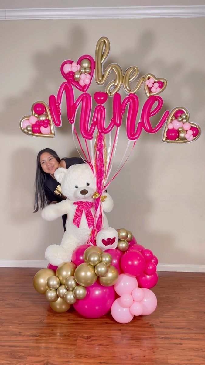 a teddy bear sitting on top of a pile of balloons with the word love in pink and gold