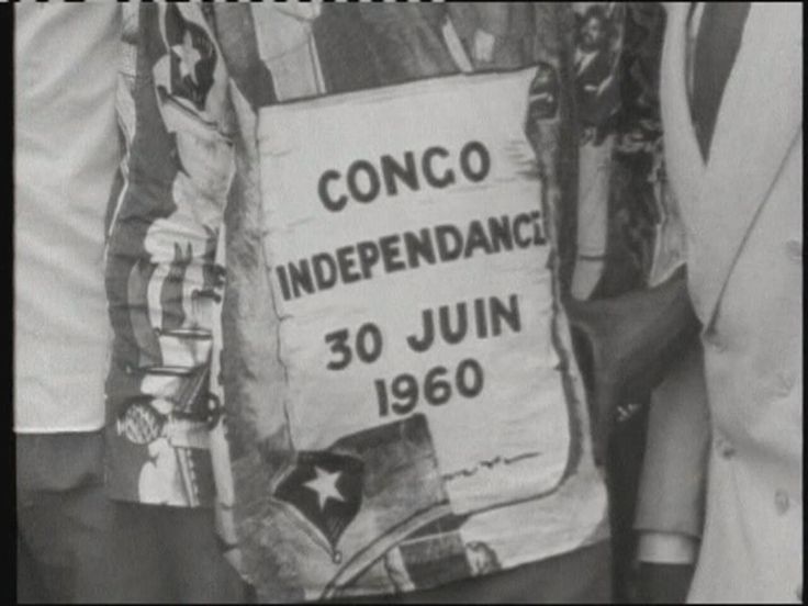 black and white photograph of two men holding a sign that reads conco independence 30 july 1960